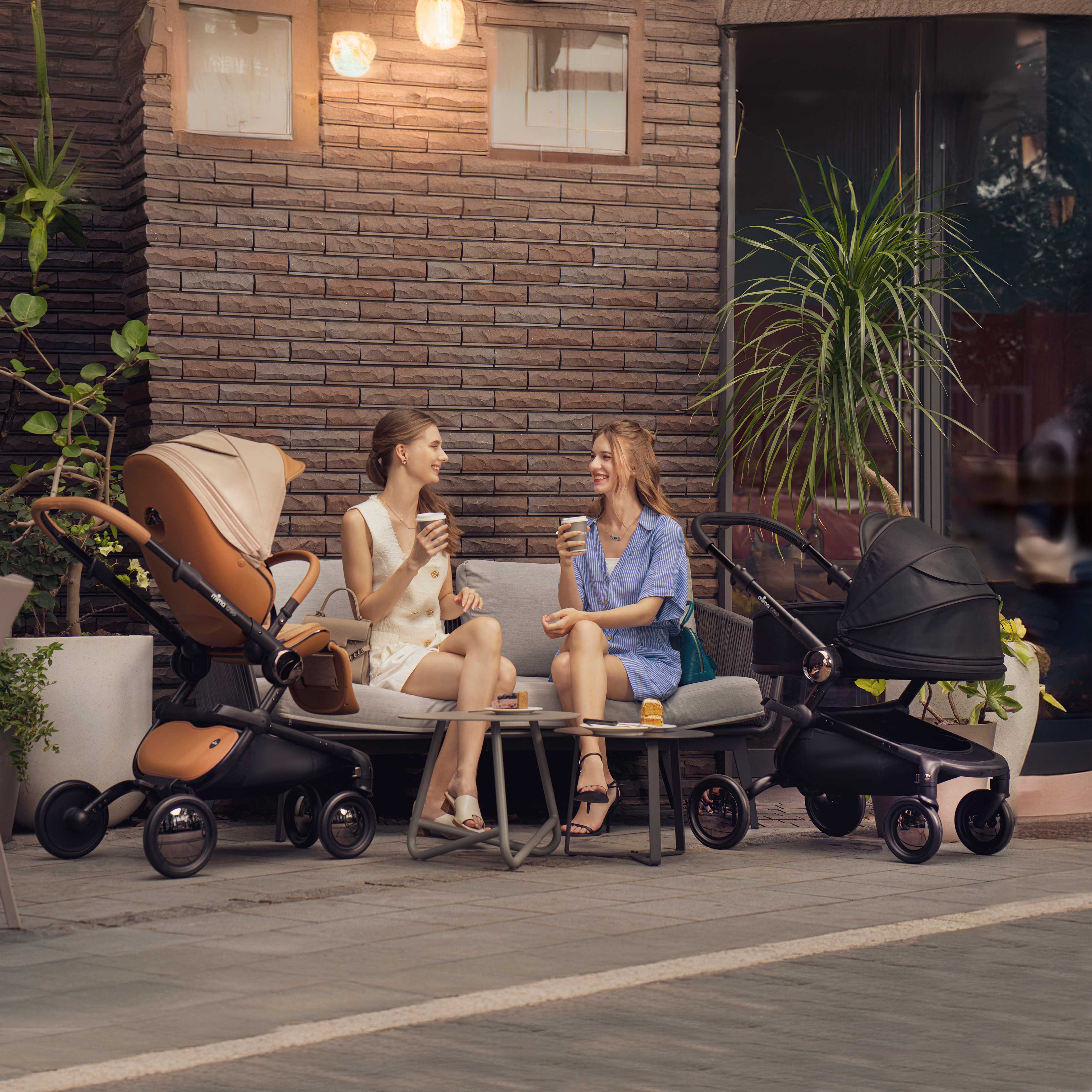 two mothers at outdoor cafe with mima creo mocha cream stroller and black bassinet for newborns