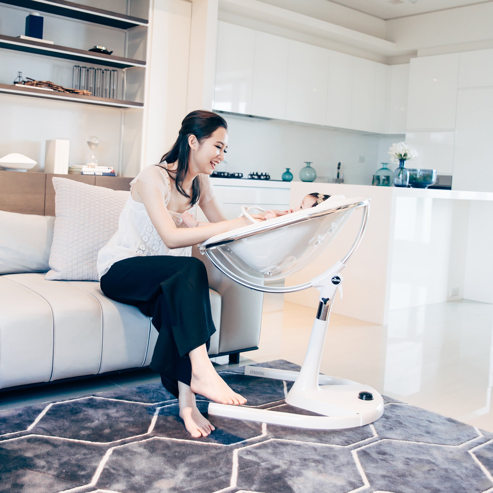 white Mima Moon 2G high chair in recline position with newborn, mother interacting, indoor living room