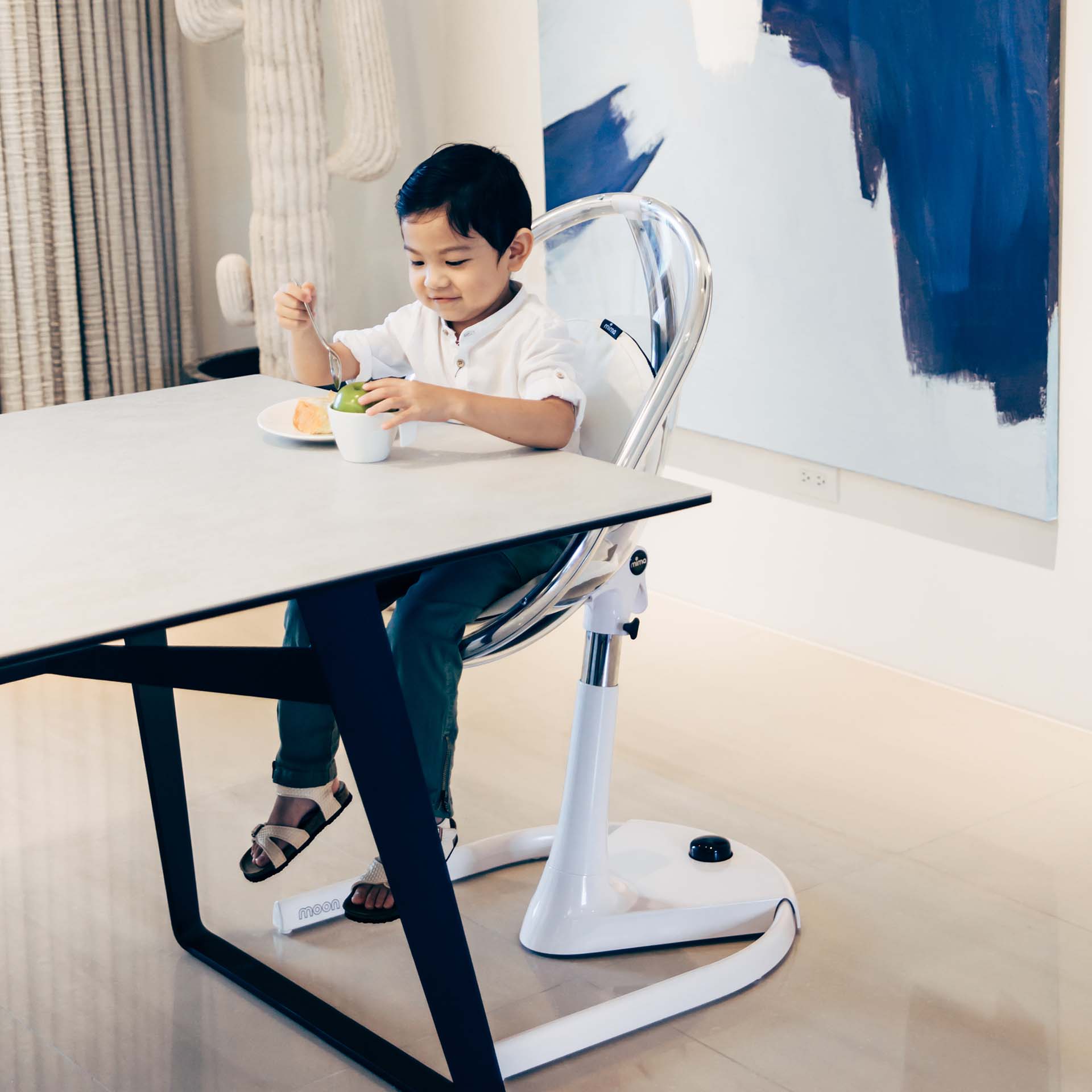 white Mima Moon 2G high chair in junior chair mode with toddler eating, indoor dining area