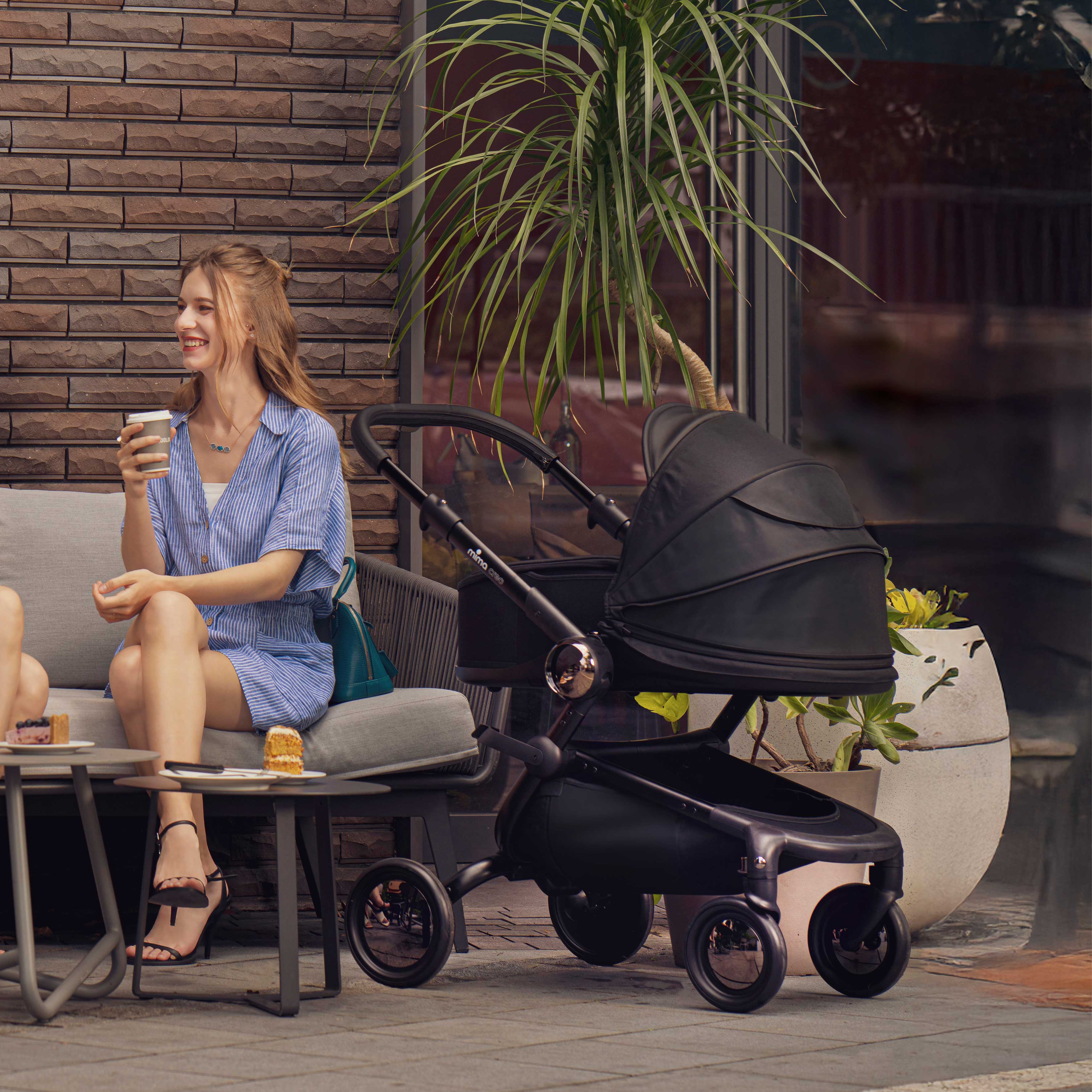 mother sitting and chatting with others beside mima creo black bassinet