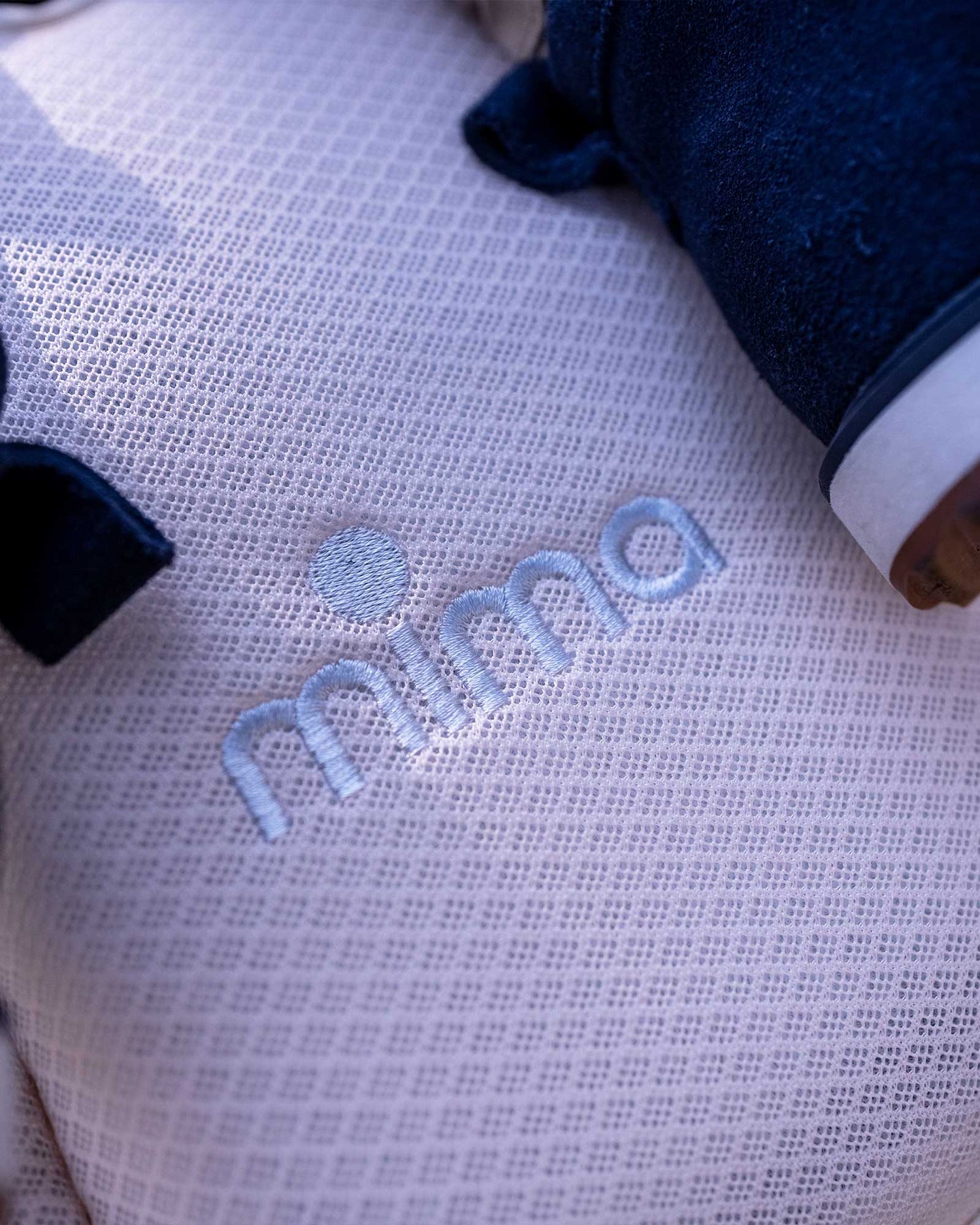Close-up of Mima® Flo Donut Cooling Seat Pad on a Mima® Creo Stroller in a park, highlighting the embroidered Mima logo on a breathable mesh fabric, designed for comfort and style.