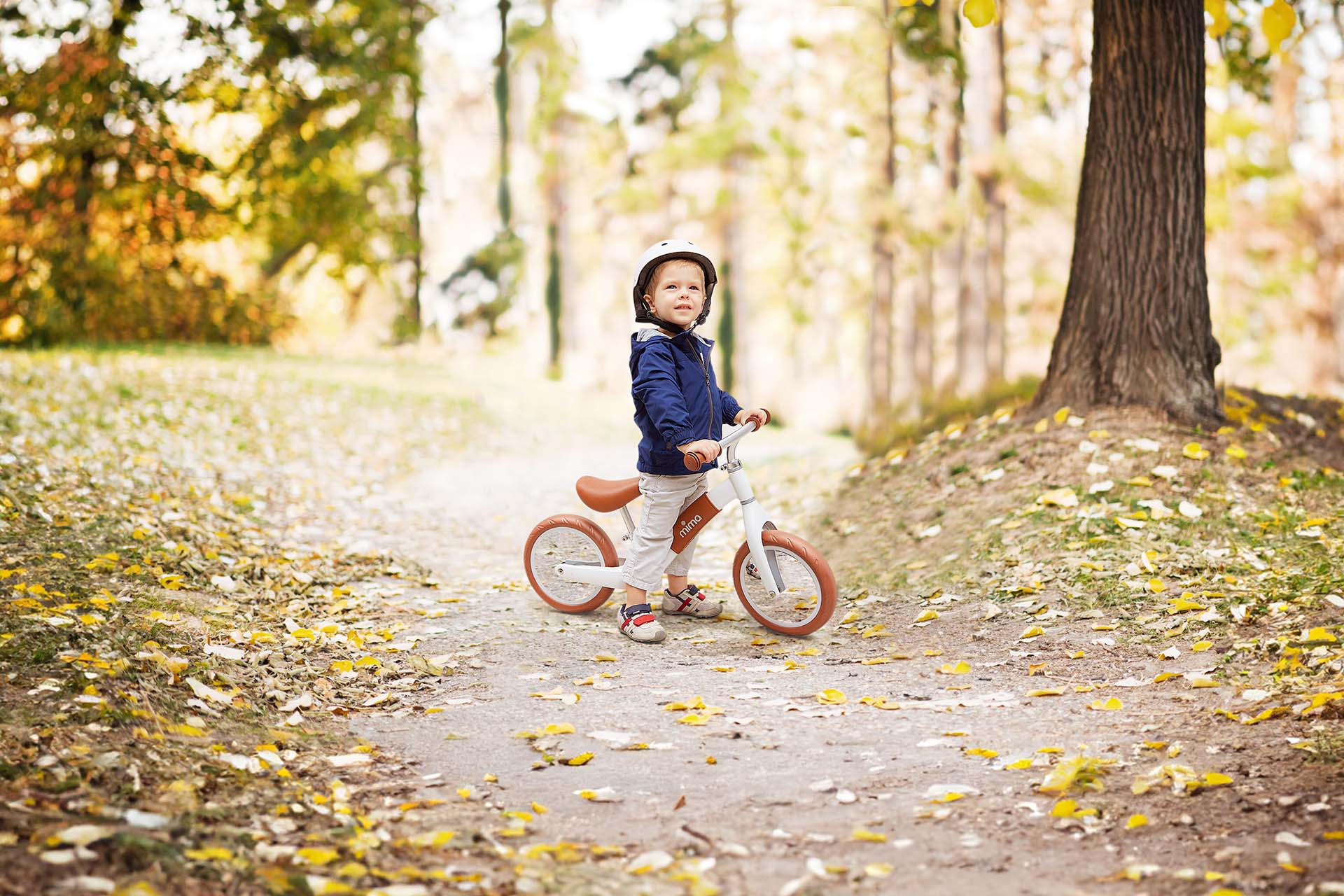 Boy wearing helmet, riding Mima® Zoom White balance bike on mountain trail