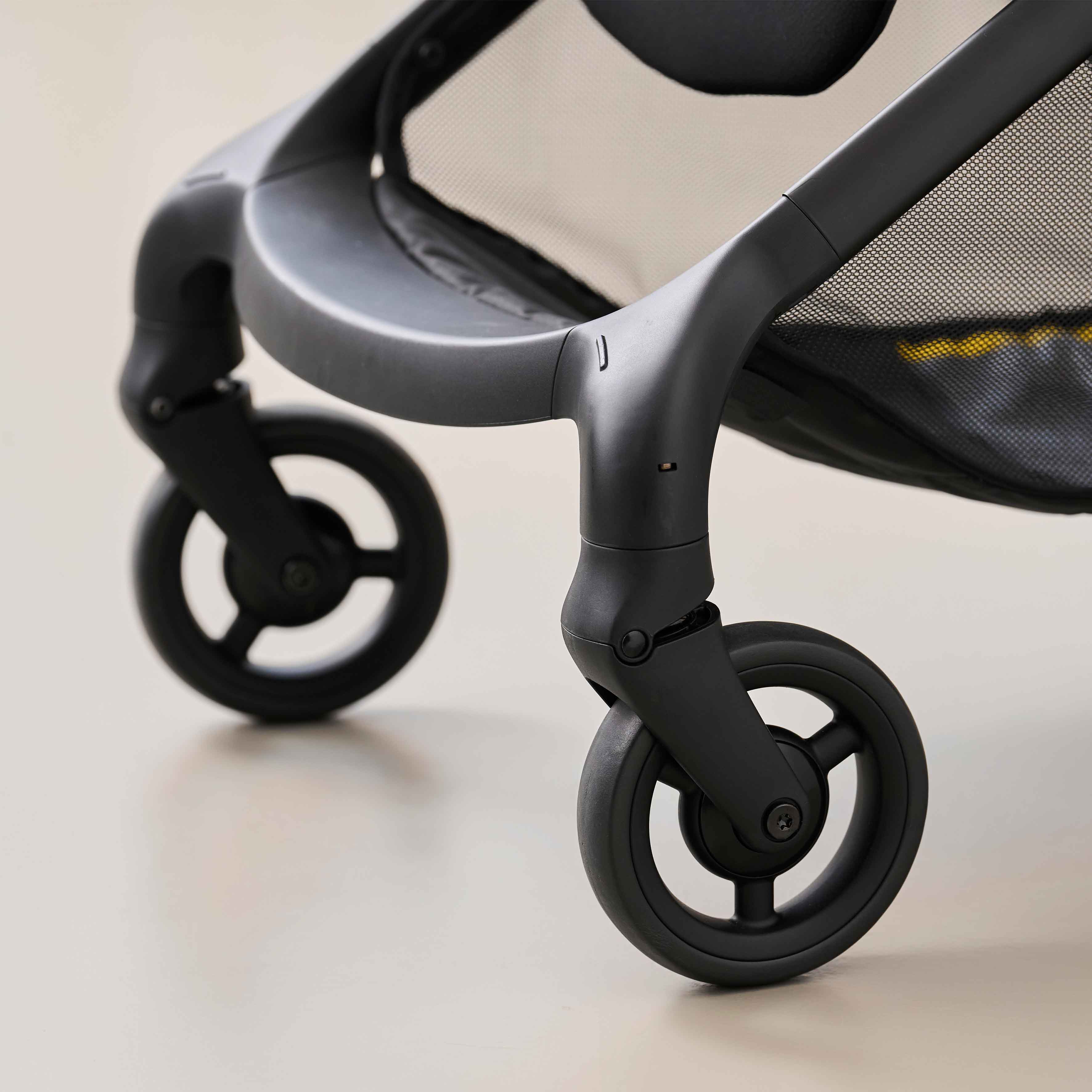 close up of front wheels on mima miro mocha cream compact travel stroller