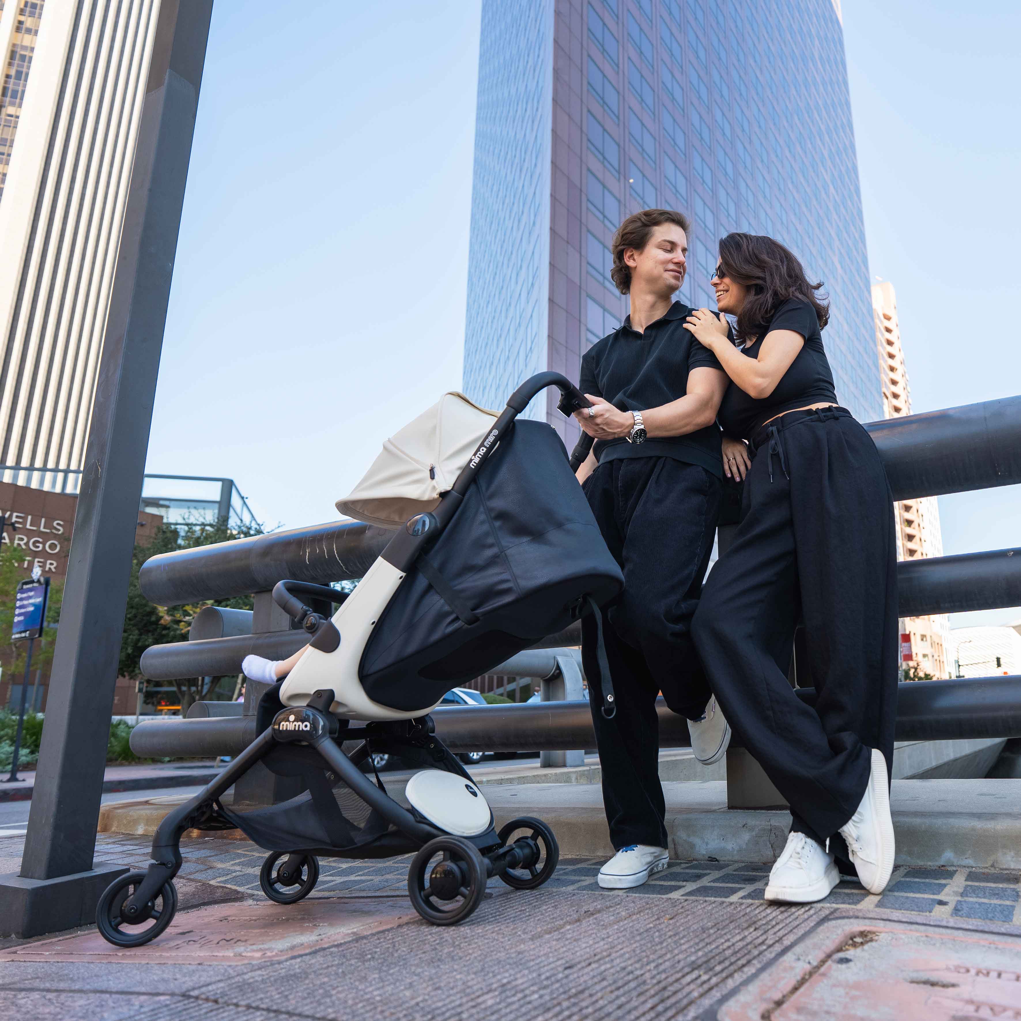 parents standing next to fully reclined mima miro stroller in white on a city street with skyscraper