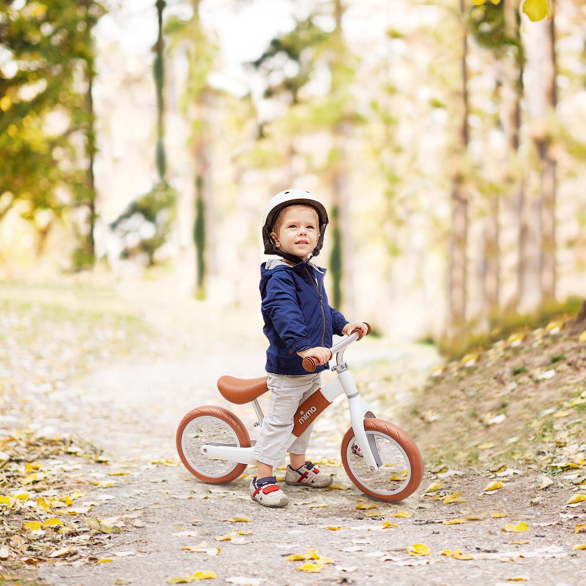 Boy wearing helmet, riding Mima® Zoom White balance bike on mountain trail