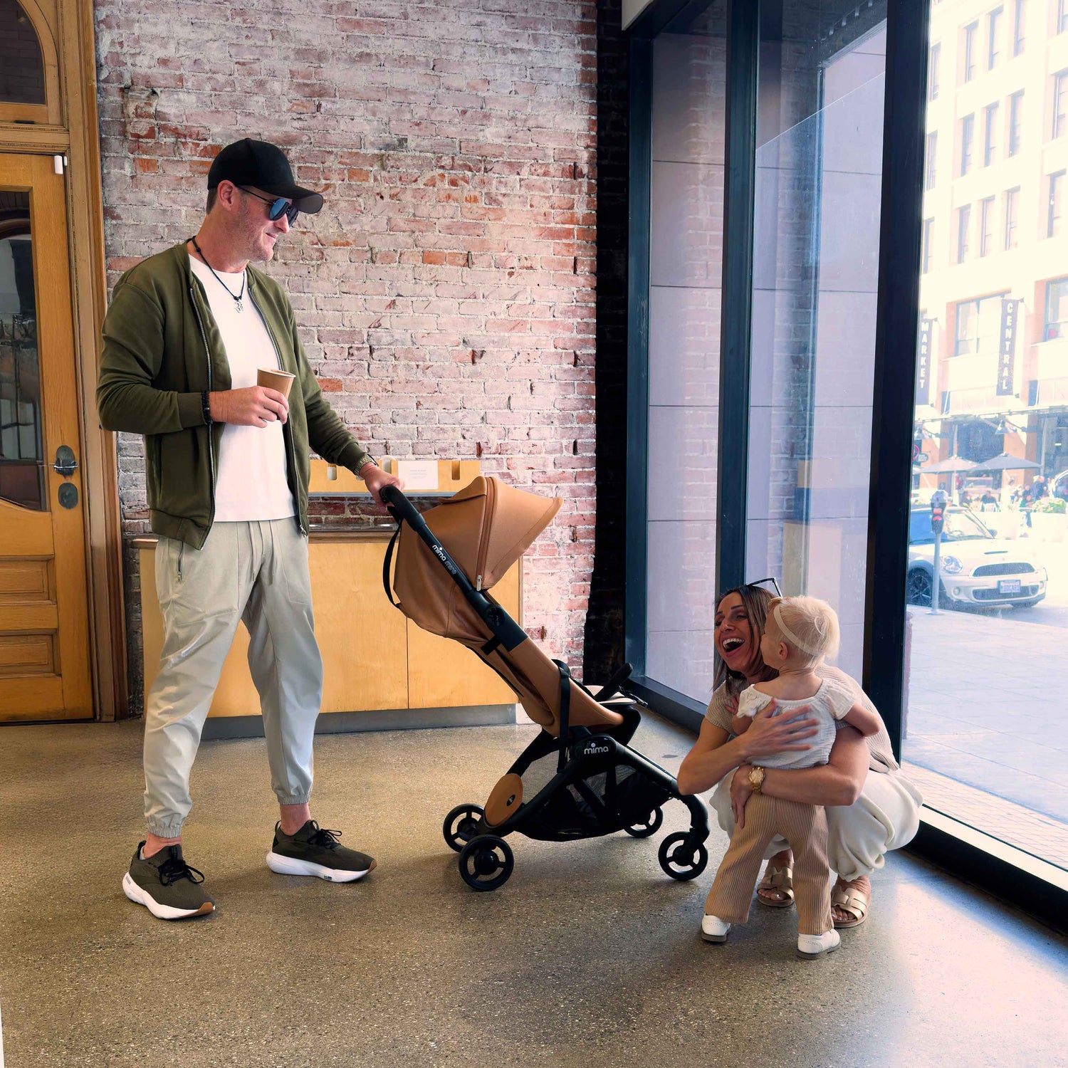 family indoors near a brick wall with toddler and mima miro stroller in mocha cream 