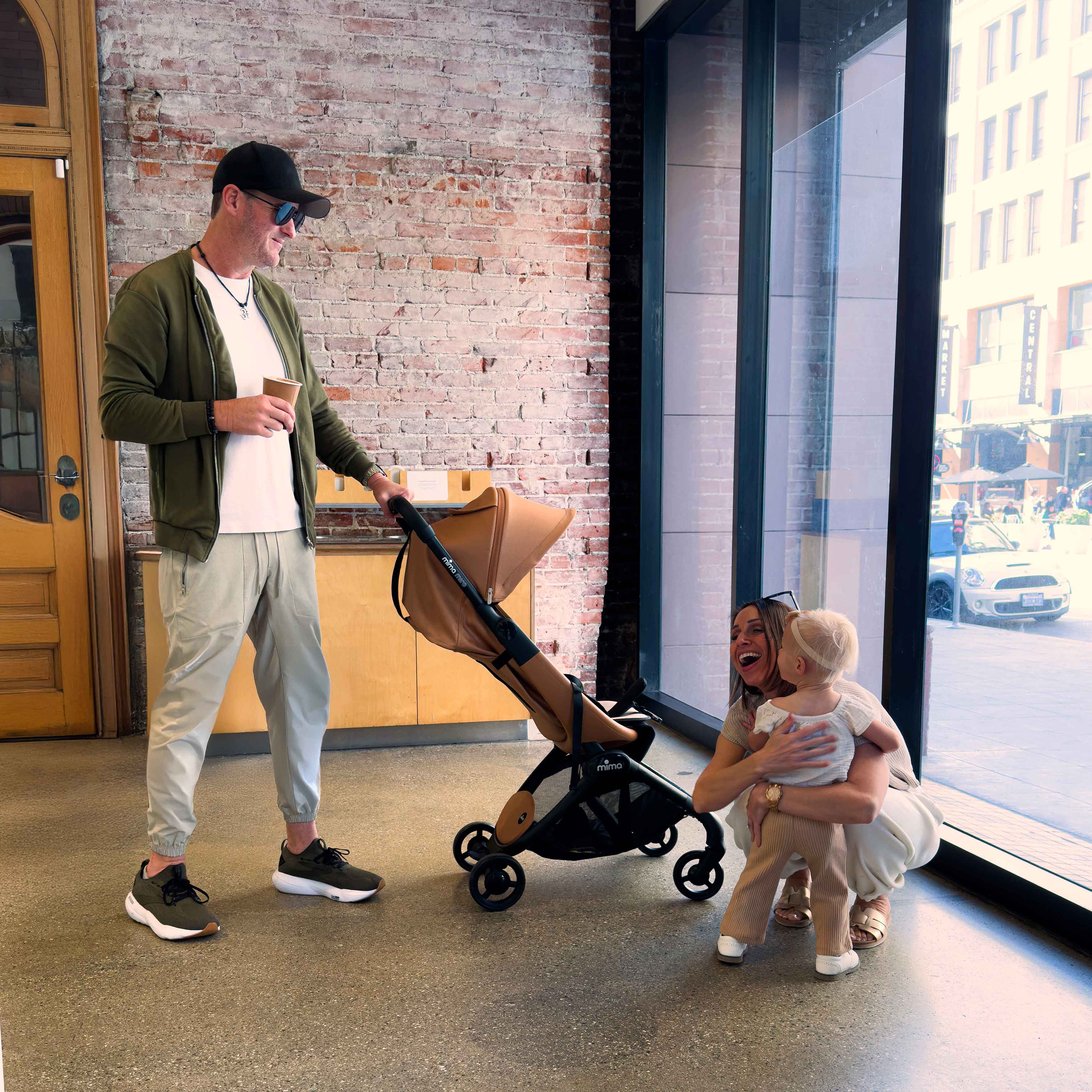 family indoors near a brick wall with toddler and mima miro stroller in mocha cream 
