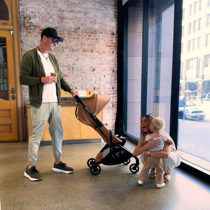 family indoors near a brick wall with toddler and mima miro stroller in mocha cream 