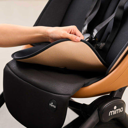 close up of hand lifting the reversible seat pad on mima miro compact travel stroller in mocha cream to show light underside 