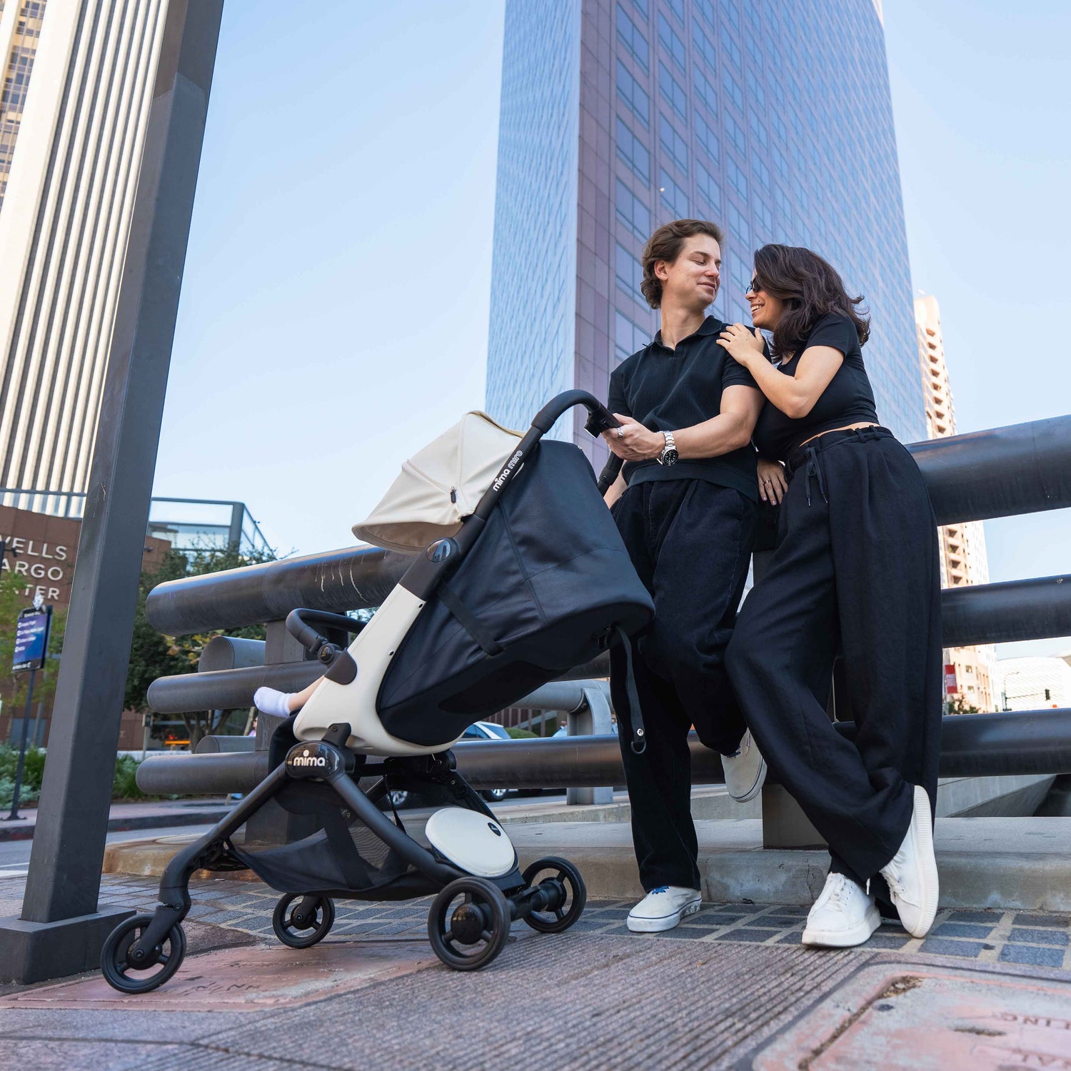 parents standing next to fully reclined mima miro stroller in white on a city street with skyscraper 